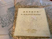 Close-up image of a pure silk hand embroidered handkerchief with floral embroidery and packaging showing Chinese text