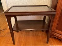 Front view of the mahogany wall table showing the glass top and lower shelf.