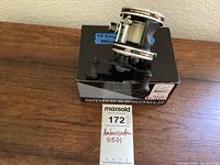 Fishing reel on top of original Abu Garcia Ambassadeur box with MaxSold tag visible.