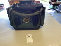 Green fabric Cabela's Outdoor Gear tackle bag to hold fishing tackle and accessories.