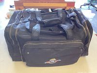 Black soft nylon fishing carry bag with multiple zippered compartments and embroidered fish logo