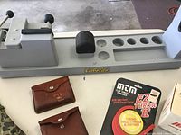 Full view of Cabela's instrument cleaner with two small leather cases and MTM EZ Throw II clay target thrower in packaging.