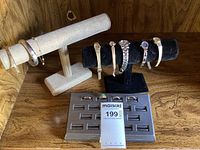 Photo showing ladies watches on black and beige display stands with 2 bracelets on beige stand and 5 watches on black stand plus gray ring display holding four rings.