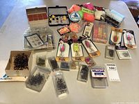 Wide view of all fly fishing supplies including lures, hooks, beads, fishing wire, and other accessories arranged on table.