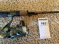 Fishing rod and spinning reel lying on carpet with MaxSold tag showing lot number.