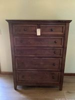 Front view of the chest showing five drawers with Tuscan finish and black round pull knobs.