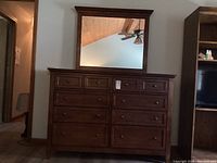 Full view of solid wood dresser with eight drawers and matching mirror above it, showing its traditional style and dark brown finish.