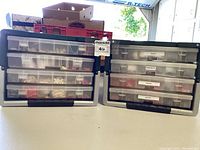 Photo showing two multi-tiered tackle boxes with several clear plastic drawers filled with fishing lures and tackle, labeled by content type.