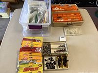 Overview photo showing multiple boxes and containers of fishing jigs, lures and tackle on a table