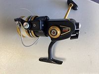 Photo of black and gold PENN 450 SS fishing reel showing side view with fishing line on spool.