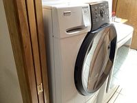 Front left angle of white Kenmore front-loading washer next to dryer showing round glass door and white body