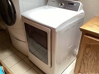 Samsung white front-load dryer adjacent to stacked washer-dryer setup