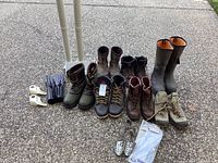 Various sports boots and boot and glove dryer with accessories arranged outdoors on pavement