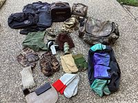 Photo of the assortment of duffel bags, hats, gloves, and mittens spread on the ground.