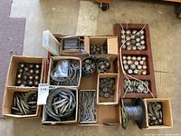 Wide overview of the entire assortment showing the various shapes and sizes of fishing weights arranged in boxes and containers.