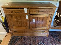 Front view showing two drawers, two cabinet doors, floral carvings, and metal drawer pulls and door handles.