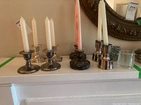 Front view of all candle holders and candles displayed on a white mantel, showing the different styles and colors