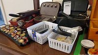 Wide view of jewelry case, grooming cases, two baskets with curling club pins and awards arranged on a table