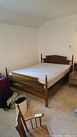 Full view of bed frame with mattress in bedroom setting, showing the headboard, footboard, and side rails.