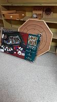 Photo showing Vegas Casino Trio boxed game with wooden maze puzzle board behind