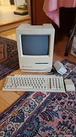 Front view of Macintosh Classic II with keyboard and mouse on rug