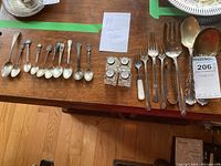 All flatware pieces and salt shakers laid out on wooden table