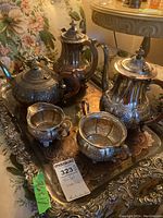 Overall view of the silverplated tea and coffee set on an ornate serving tray, highlighting the wooden handles and detailed engravings.