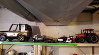 Wide view of toy vehicles on shelf including Tonka Jeep, white toy car, red fire truck, black toy truck, and Case IH tractor.