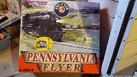 Front of Lionel Pennsylvania Flyer Train Set box showing product image, features like powerful headlight, real smoke, realistic air whistle, accessories including bridge, and model number 6-30018.