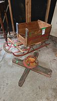 Child's wooden sled with attached Ontario apples crate and Christmas tree stand on floor.