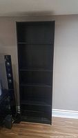 Front view of one black wooden book shelf showing shelves and overall condition