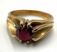 Front left angled view of ring showing red gemstone and band design.