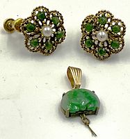 Pair of screw-back earrings and jadeite pendant on white surface