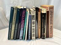 Books standing upright showing titles related to Asian art, mainly Japanese prints and paintings, with one green apple for size reference (3x3 inches).