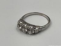 Side view of ring on white background showing three round diamonds and band detail