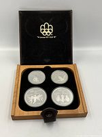 Open wooden and leather case showing four proof coins in black velvet inserts