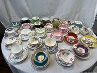 Wide view of 26 assorted tea cups and saucers displayed