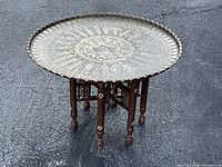 Full view of table from front-left showing brass tray and folding legs