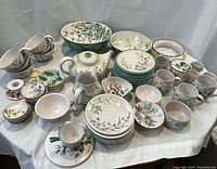 Overview of entire hand painted pottery assortment on white cloth