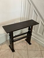 Front right angled view of side table showing carved top, supports and stretcher base