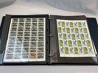 Opened black binder showing full sheets of mint Canadian stamps, including historical figure designs and aircraft