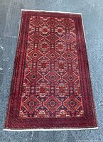 Top down view of large rectangular red rug showing full geometric pattern and detailed borders.