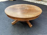 Round oak coffee table full view angled on asphalt surface