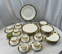 Full set displayed with all cups, saucers, plates, and serving dishes arranged with green apple for scale.