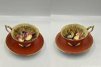 Two hand painted Aynsley teacup and saucer sets shown side by side