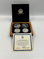 Open wood and leather case displaying four proof coins and certificate on black velour interior