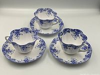 Three cups and saucers arranged on white background showing overall lot