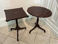 Two side tables together, one round and one square top, both with tilt-top design and dark wood finish
