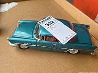 Top side view of the teal blue die cast 1955 Buick Century model car showing red interior and chrome accents on the side and wheels.