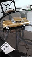 Full side view of the gold and silver 1958 Studebaker Golden Hawk diecast model car on glass table